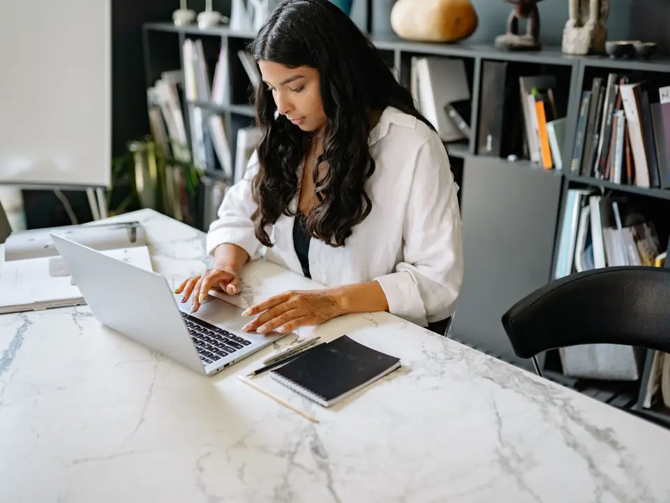 A recruiter working through applications on a laptop at a bright office desk